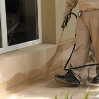 General pest control technician spraying exterior perimeter around a home in Tuscaloosa, AL