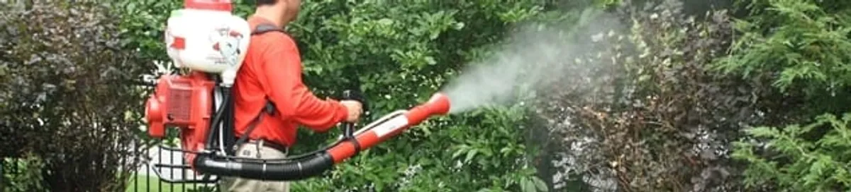 Mosquito control technician fogging shrubs and landscaping for mosquito treatment in Tuscaloosa, AL